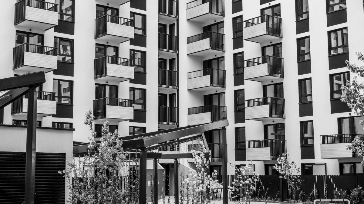 Edifício residencial contemporâneo com varandas e pátio interno, fotografado em preto e branco.