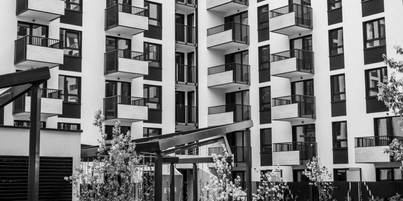 Edifício residencial contemporâneo com varandas e pátio interno, fotografado em preto e branco.