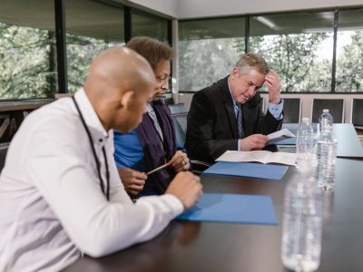 Equipe diversa de profissionais analisa documentos durante uma reunião de trabalho.