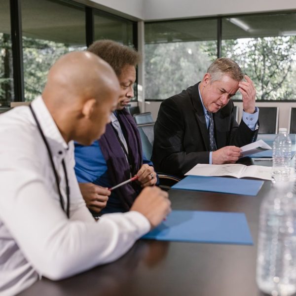 Equipe diversa de profissionais analisa documentos durante uma reunião de trabalho.