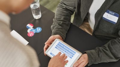 Pessoa utiliza um tablet em um posto de atendimento eleitoral durante o processo de registro.