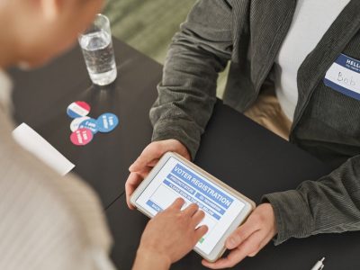 Pessoa utiliza um tablet em um posto de atendimento eleitoral durante o processo de registro.