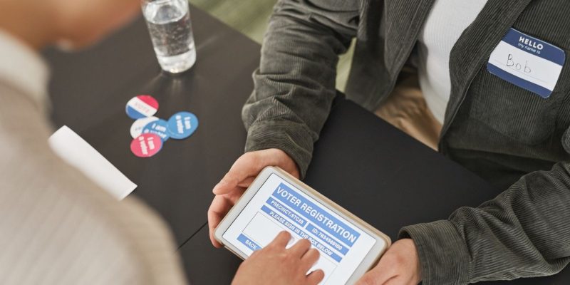 Pessoa utiliza um tablet em um posto de atendimento eleitoral durante o processo de registro.