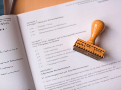 Close de um documento jurídico com um carimbo de madeira sobre ele, em uma mesa.