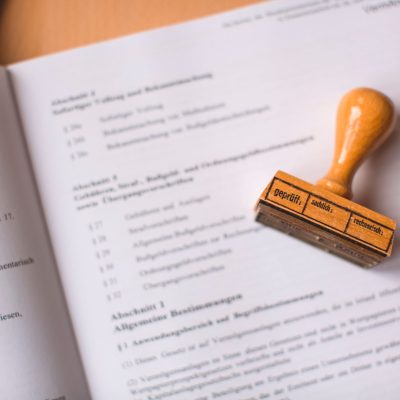 Close de um documento jurídico com um carimbo de madeira sobre ele, em uma mesa.