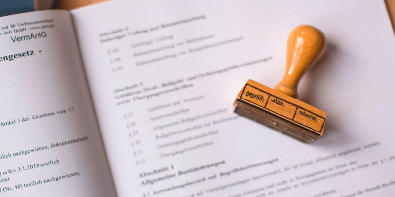 Close de um documento jurídico com um carimbo de madeira sobre ele, em uma mesa.