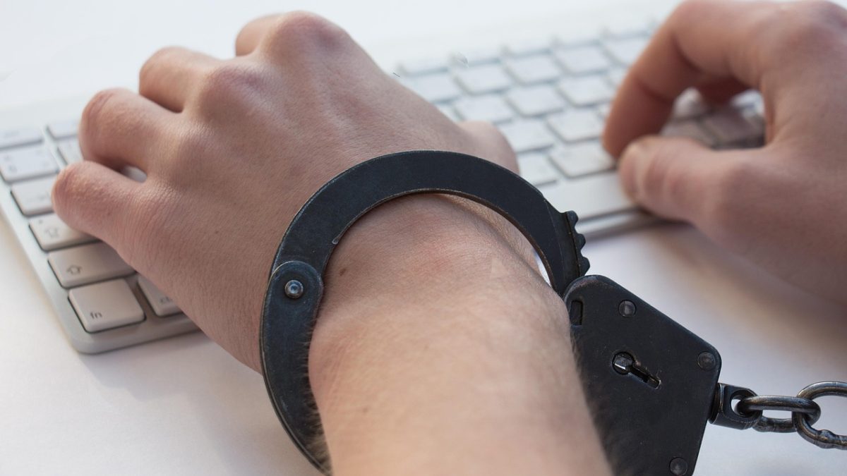 Mãos algemadas sobre um teclado, em uma representação conceitual da dependência em jogos de azar e da perda de controle.