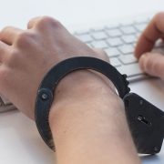 Mãos algemadas sobre um teclado, em uma representação conceitual da dependência em jogos de azar e da perda de controle.