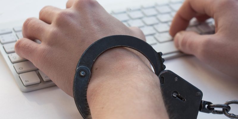 Mãos algemadas sobre um teclado, em uma representação conceitual da dependência em jogos de azar e da perda de controle.